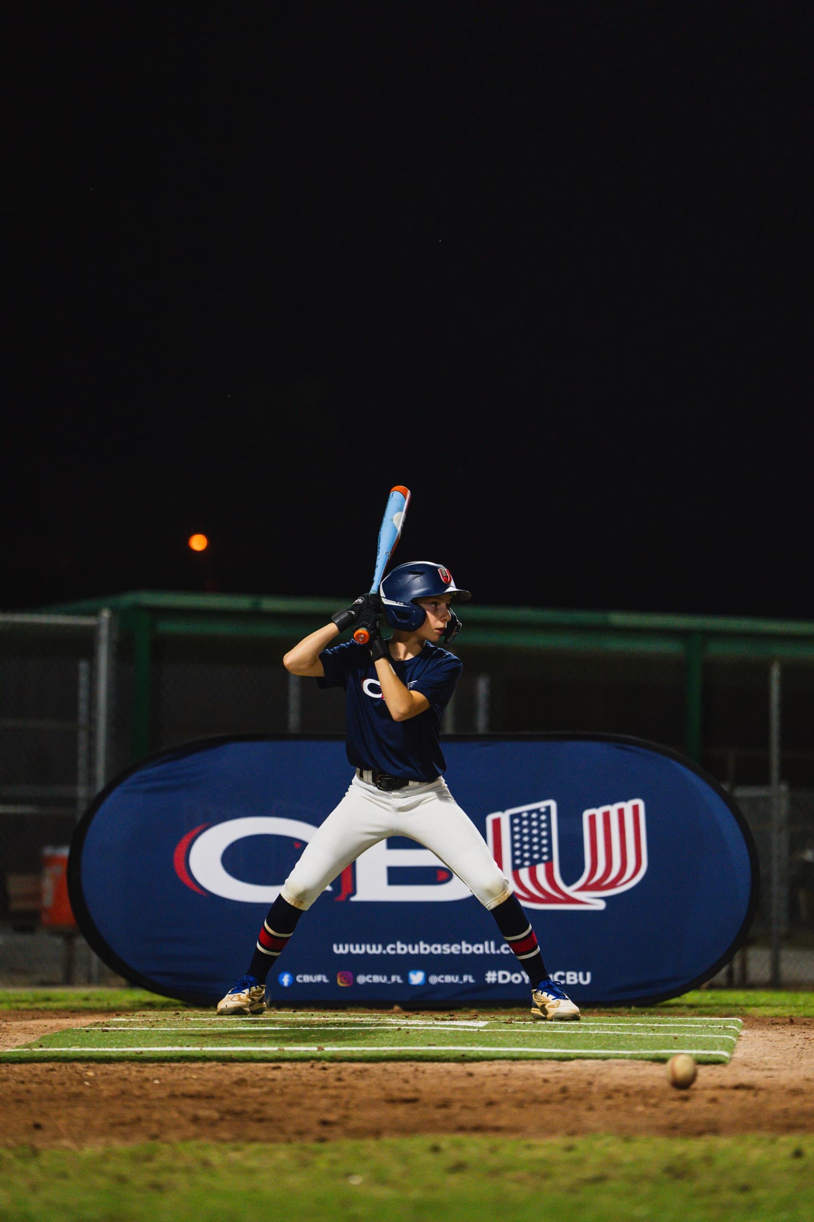 Youth player in batting stance with CBU banner